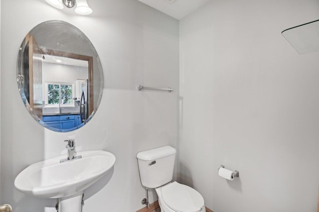half bath with toilet, a sink, and baseboards