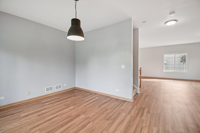 spare room featuring light wood-type flooring, baseboards, a smoke detector, and stairway