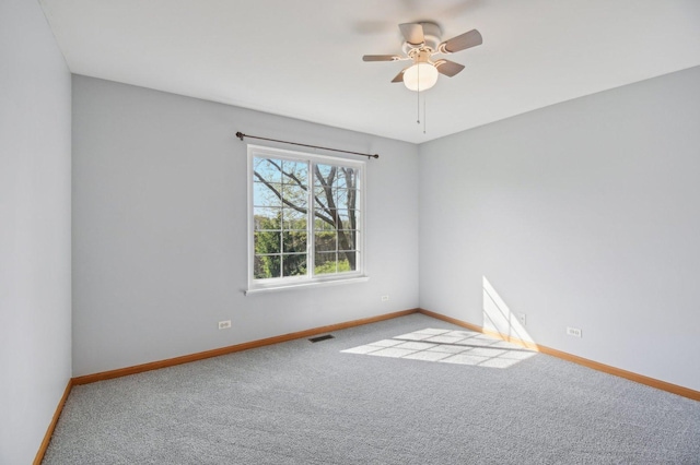 carpeted spare room featuring baseboards and ceiling fan