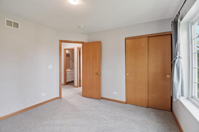 unfurnished bedroom with light colored carpet, a closet, and baseboards