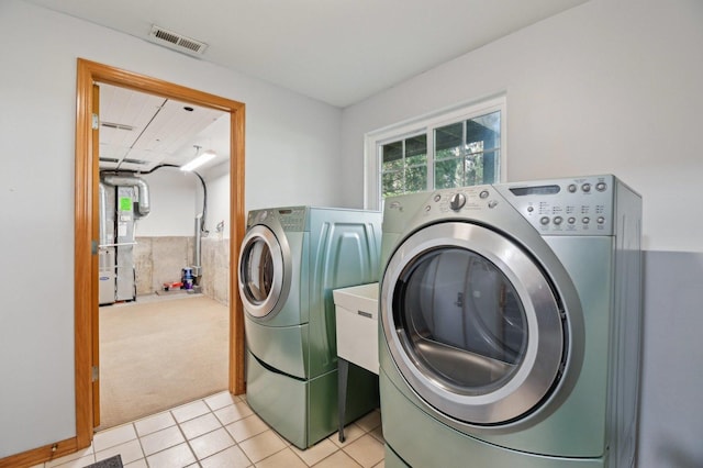laundry area with washing machine and dryer, light colored carpet, and light tile patterned floors