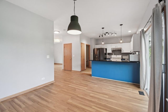 kitchen featuring stainless steel refrigerator with ice dispenser, range, dark countertops, light wood-type flooring, and white cabinetry