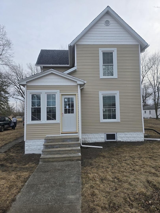 view of front of property with entry steps, a shingled roof, and a front lawn
