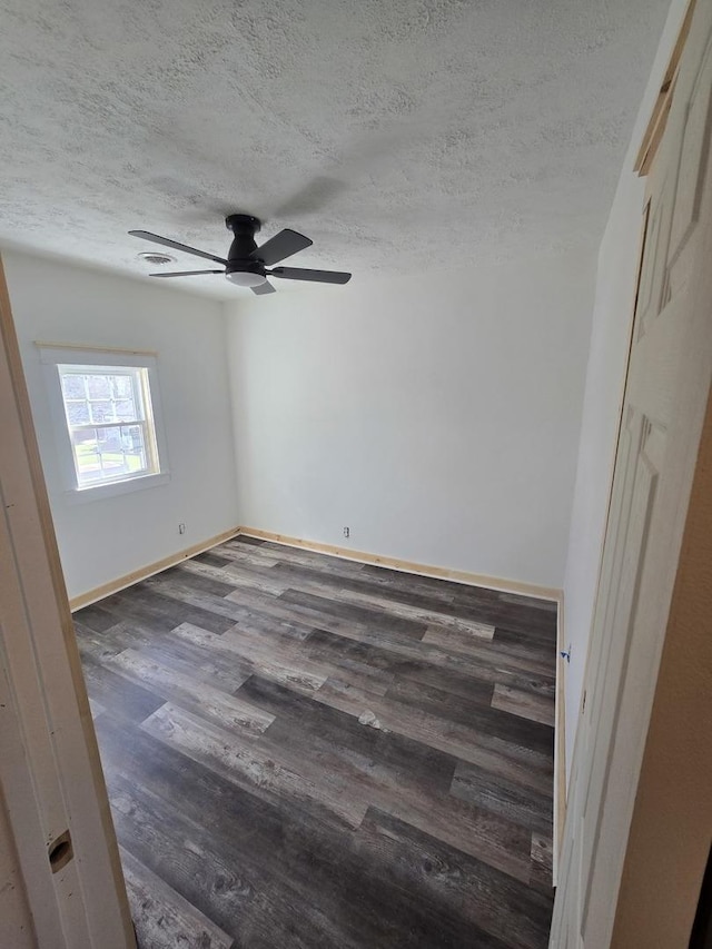 empty room featuring a textured ceiling, wood finished floors, baseboards, and ceiling fan