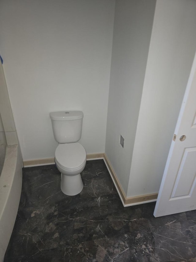 full bath with toilet, baseboards, and a tub to relax in