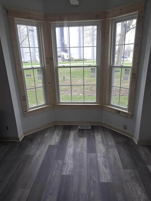 unfurnished dining area featuring plenty of natural light, baseboards, and dark wood-style floors