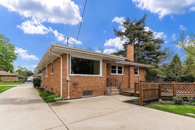 rear view of property with a chimney, brick siding, a wooden deck, and a patio area