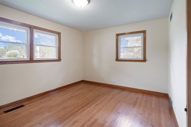 spare room with baseboards and light wood-style floors