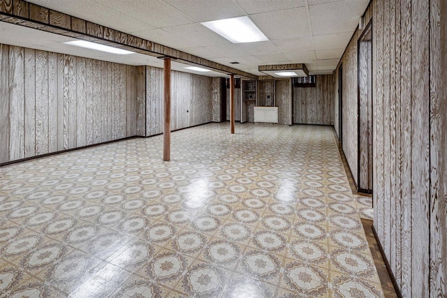 finished basement with light floors and a paneled ceiling