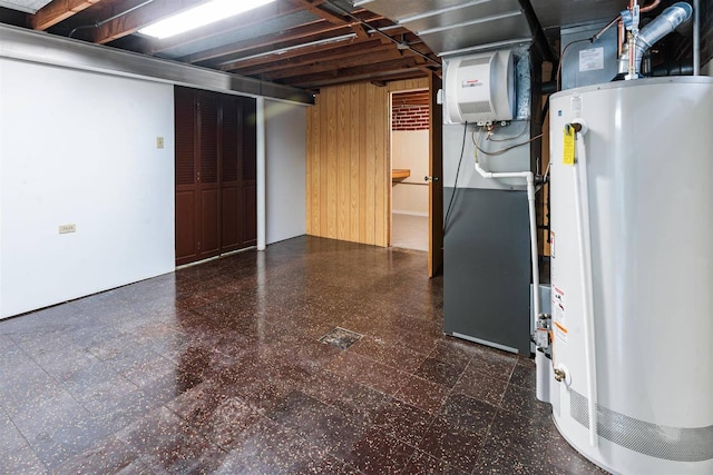 finished basement featuring tile patterned floors, water heater, and wood walls