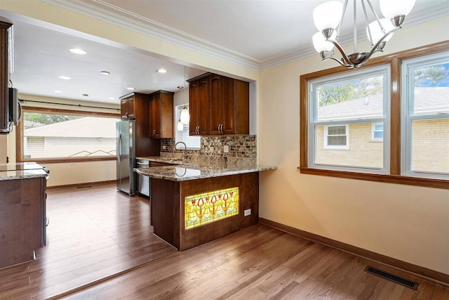 kitchen featuring appliances with stainless steel finishes, a chandelier, baseboards, light wood-style flooring, and crown molding