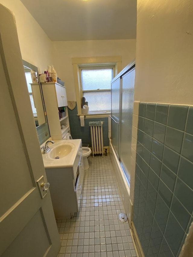 2552 N Austin Ave, Chicago, IL 60639 - bathroom featuring radiator, tile walls, tile patterned floors, toilet, and a shower with door
