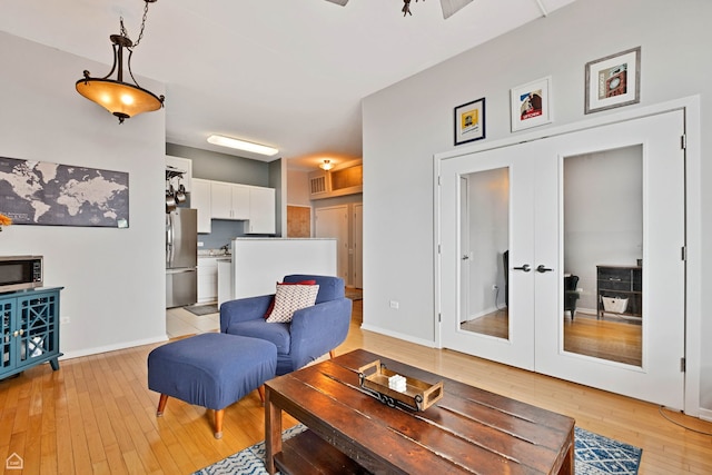 living area with light wood-type flooring, french doors, and baseboards