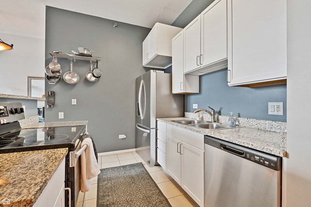 kitchen featuring appliances with stainless steel finishes, a sink, light tile patterned floors, and white cabinets
