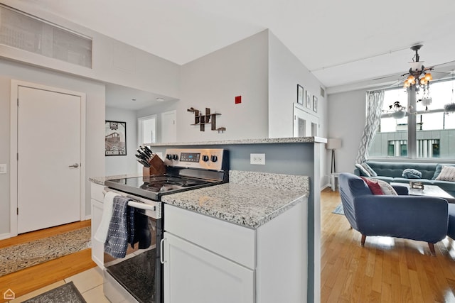 kitchen featuring stainless steel range with electric cooktop, open floor plan, white cabinetry, light stone counters, and light wood-type flooring