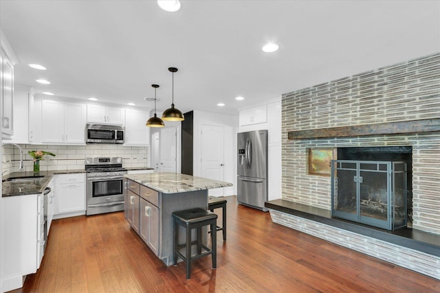 811 Hamilton Dr, Champaign, IL 61820 - kitchen featuring stainless steel appliances, a sink, dark stone countertops, a kitchen bar, and white cabinets