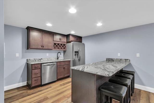 811 Hamilton Dr, Champaign, IL 61820 - kitchen with stainless steel appliances, a breakfast bar, baseboards, light stone countertops, and a peninsula