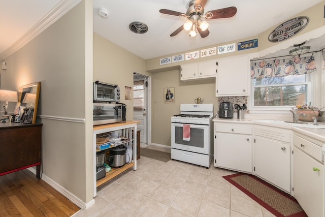 4000 Elm St, Downers Grove, IL 60515 - kitchen featuring white gas range oven, a ceiling fan, light countertops, white cabinetry, and ornamental molding