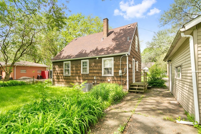 17725 Henry St, Lansing, IL 60438 - rear view of house featuring a chimney, roof with shingles, and central AC