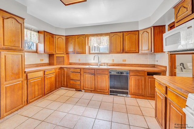 337 George Ave, Waukegan, IL 60085 - kitchen featuring black dishwasher, white microwave, a sink, brown cabinets, and backsplash