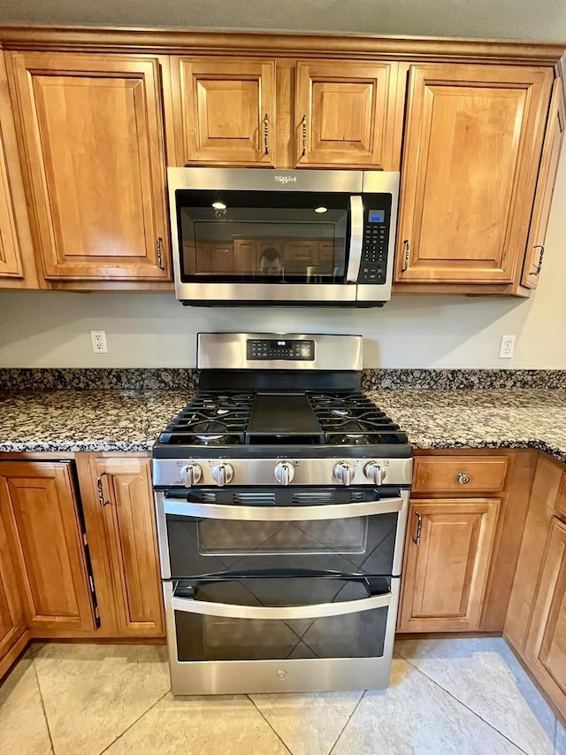 1143 N Westshore Blvd, Manteno, IL 60950 - kitchen with stainless steel appliances, brown cabinets, dark stone counters, and light tile patterned flooring