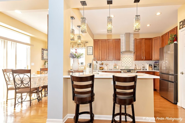 3123 Concord Ln, Wadsworth, IL 60083 - kitchen featuring freestanding refrigerator, wall chimney range hood, light countertops, light wood-style floors, and decorative backsplash
