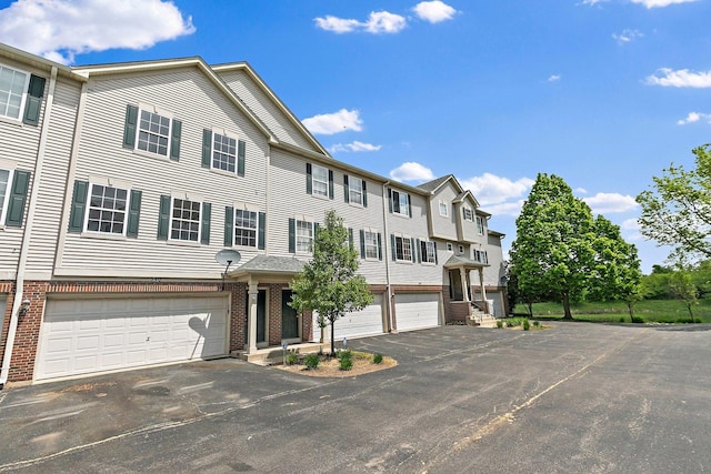 townhome / multi-family property featuring asphalt driveway, brick siding, and a garage