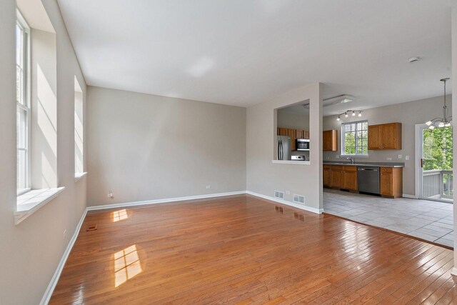 unfurnished living room featuring light wood finished floors, baseboards, and a chandelier