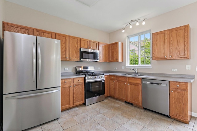 kitchen featuring stainless steel appliances, a sink, light tile patterned flooring, and brown cabinetry