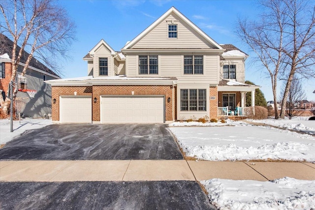 traditional home featuring asphalt driveway, a porch, a garage, and brick siding