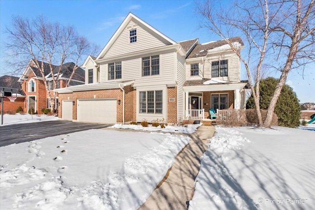 view of front facade featuring an attached garage, brick siding, a porch, and asphalt driveway