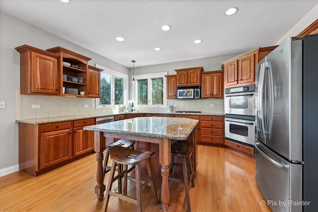 kitchen featuring stainless steel appliances, brown cabinets, light wood-type flooring, a kitchen bar, and recessed lighting