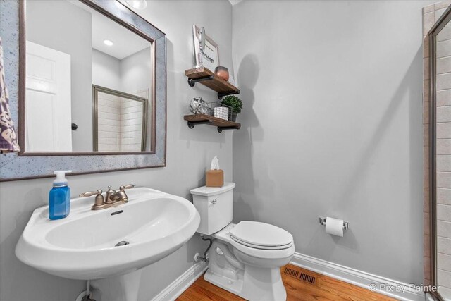 bathroom with wood finished floors, baseboards, a stall shower, and a sink