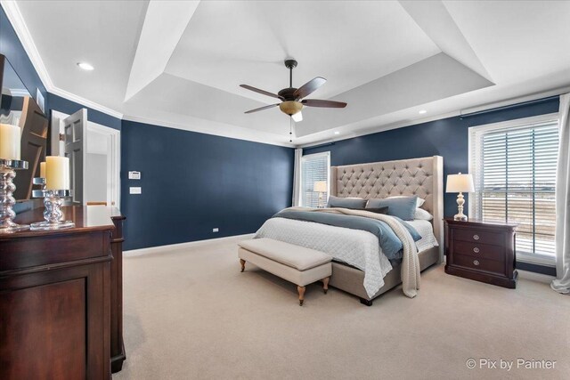 bedroom featuring a raised ceiling, light colored carpet, multiple windows, baseboards, and ornamental molding