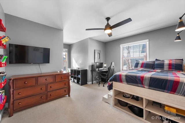 bedroom with light colored carpet, an office area, baseboards, and a ceiling fan