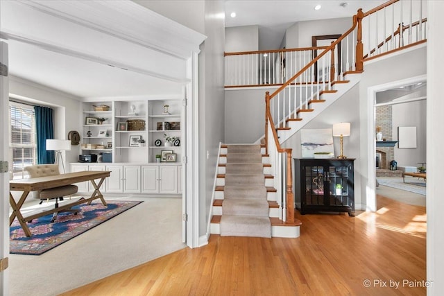 stairs featuring wood finished floors, baseboards, a brick fireplace, and recessed lighting