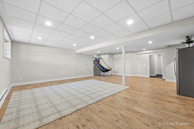 finished basement with freestanding refrigerator, light wood-style floors, baseboards, and recessed lighting