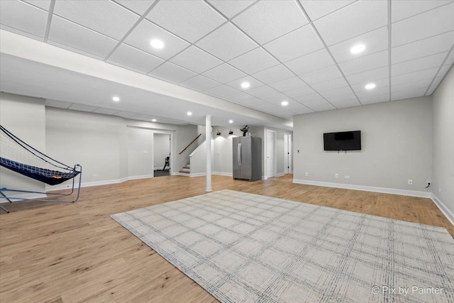 finished below grade area with freestanding refrigerator, light wood-type flooring, stairs, baseboards, and recessed lighting