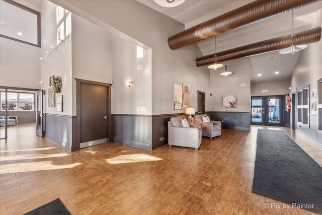 reception featuring a high ceiling, a wainscoted wall, and french doors