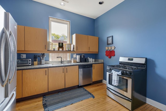3809 N Kenmore Ave, Chicago, IL 60613 - kitchen featuring appliances with stainless steel finishes, a sink, light wood-style floors, and baseboards