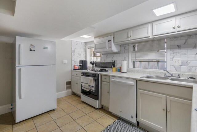 3809 N Kenmore Ave, Chicago, IL 60613 - kitchen featuring white appliances, a sink, light countertops, light tile patterned floors, and tasteful backsplash