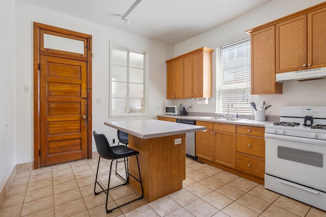 3809 N Kenmore Ave, Chicago, IL 60613 - kitchen with white appliances, under cabinet range hood, a sink, light countertops, and a kitchen breakfast bar