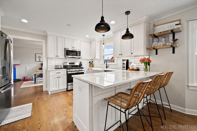 20 S Cambridge Dr, Geneva, IL 60134 - kitchen with stainless steel appliances, ornamental molding, a peninsula, white cabinetry, and a kitchen bar