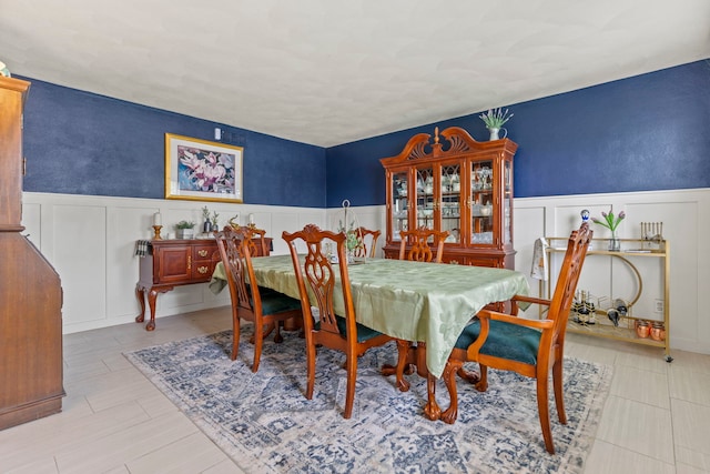 dining space featuring a decorative wall and a wainscoted wall