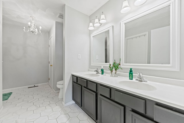 bathroom featuring toilet, a chandelier, double vanity, tile patterned flooring, and baseboards
