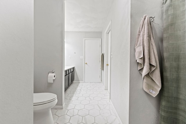 bathroom with tile patterned flooring, vanity, toilet, and baseboards