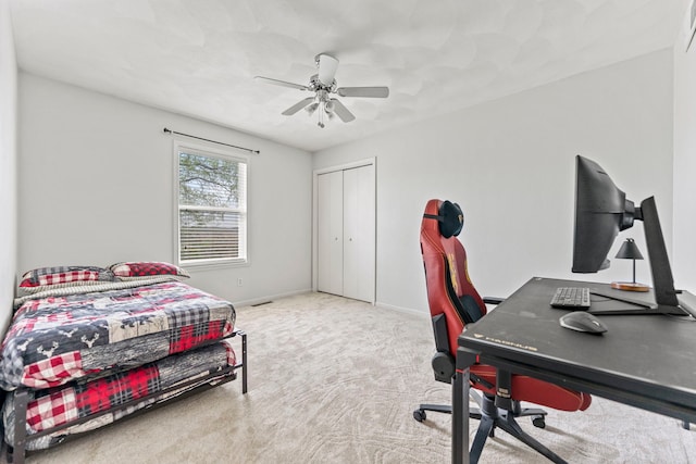 carpeted bedroom with an office area, a closet, baseboards, and a ceiling fan