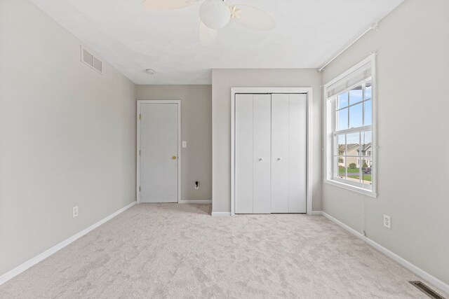 unfurnished bedroom featuring carpet floors, a closet, baseboards, and a ceiling fan