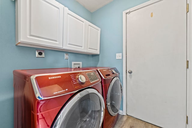 clothes washing area featuring washing machine and dryer, cabinet space, light wood-type flooring, and baseboards