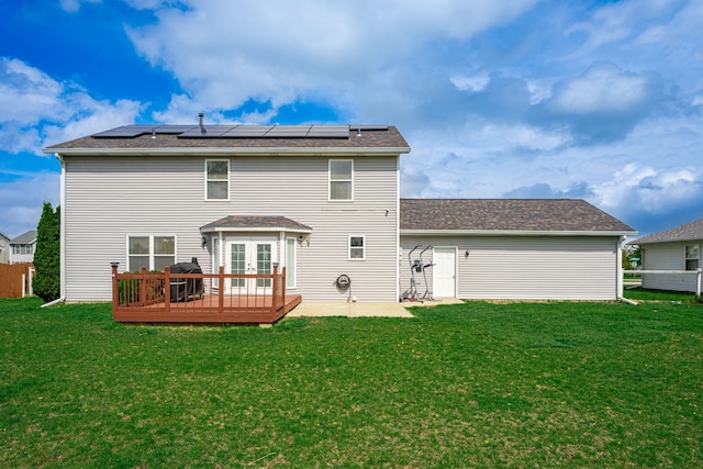back of property featuring french doors, a deck, solar panels, and roof with shingles